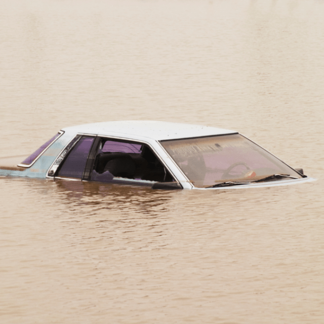 Automobile sommersa dall’acqua fino al livello del finestrino durante un’alluvione.